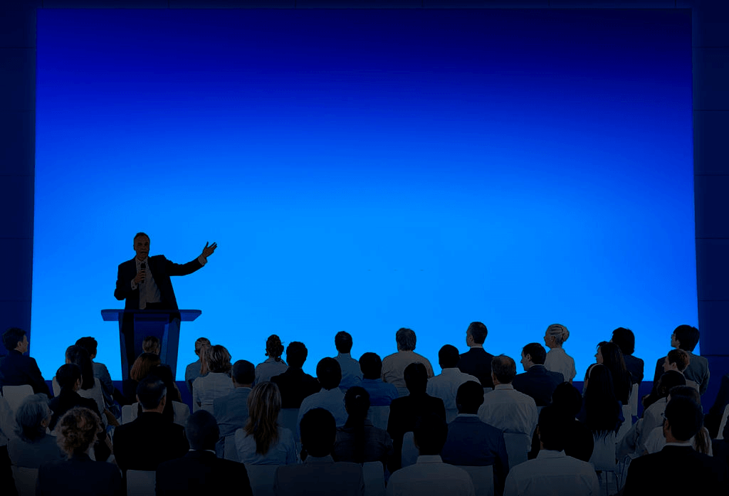A corporate speaker addressing an audience from a lectern